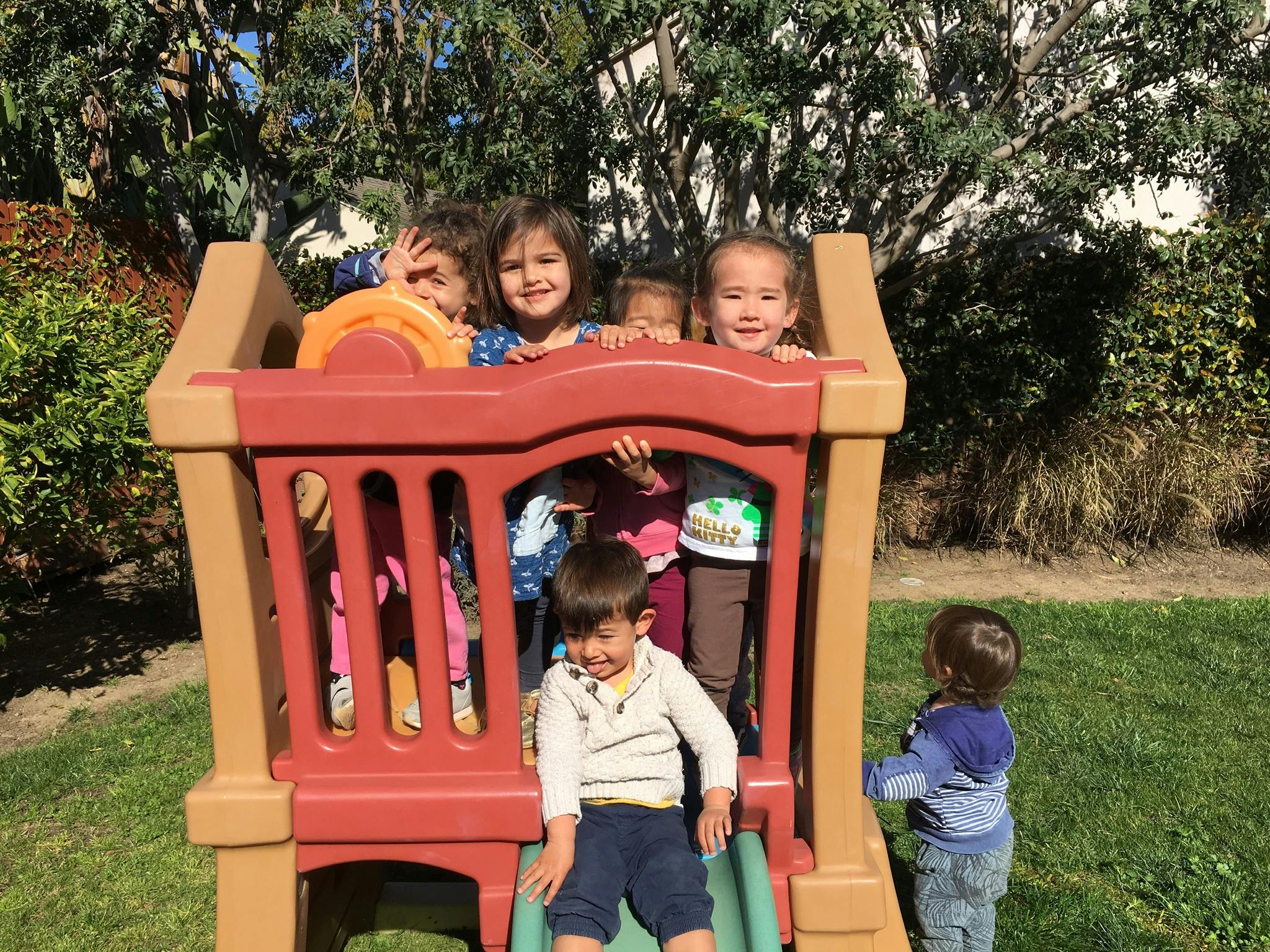 Children playing on a red and tan playground structure