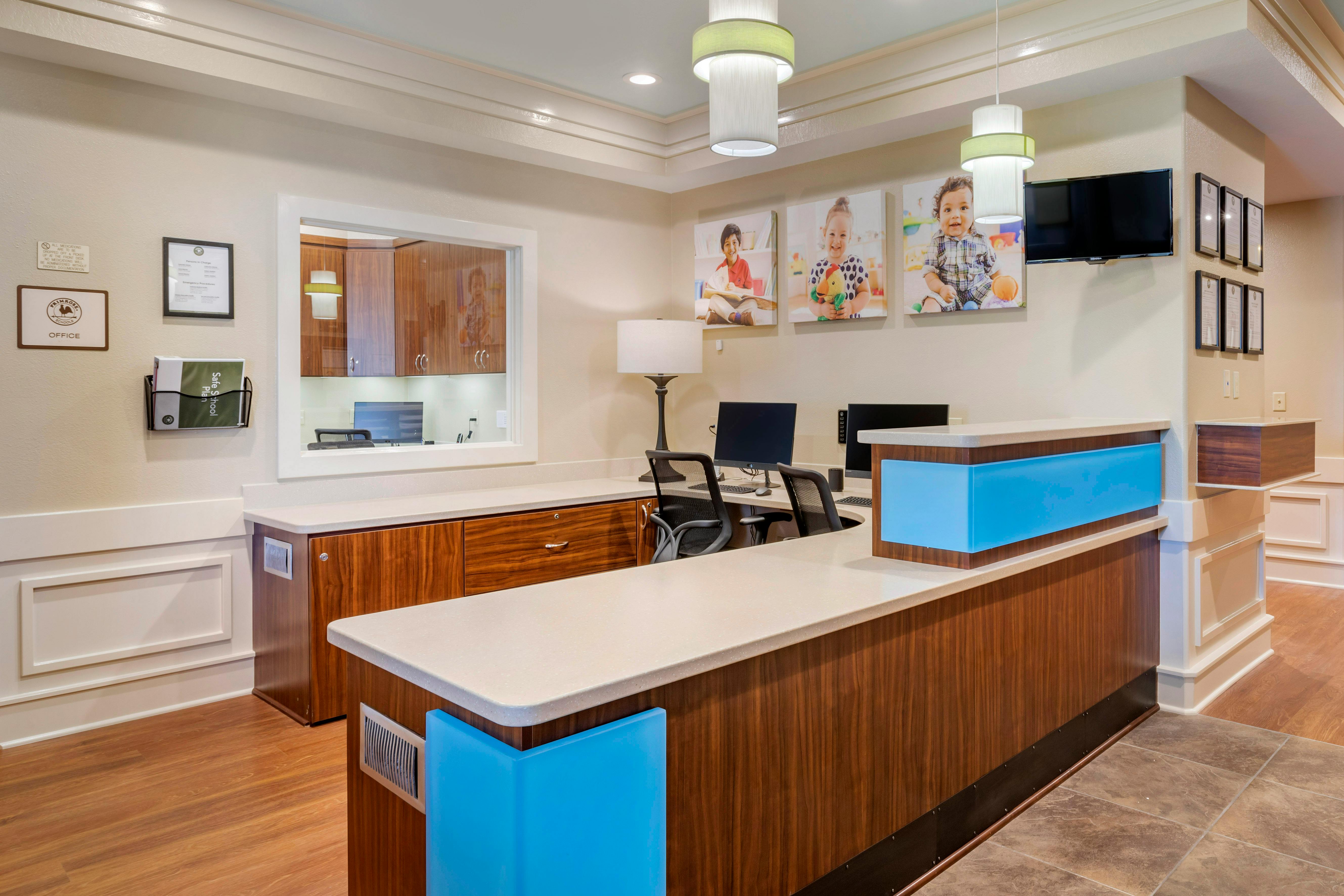 Reception area with a light-colored counter, wood paneling, and computer workstations