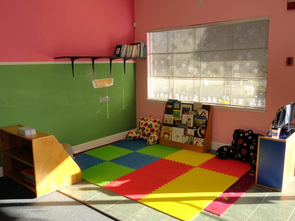 Playroom with colorful floor mats, book display, and window