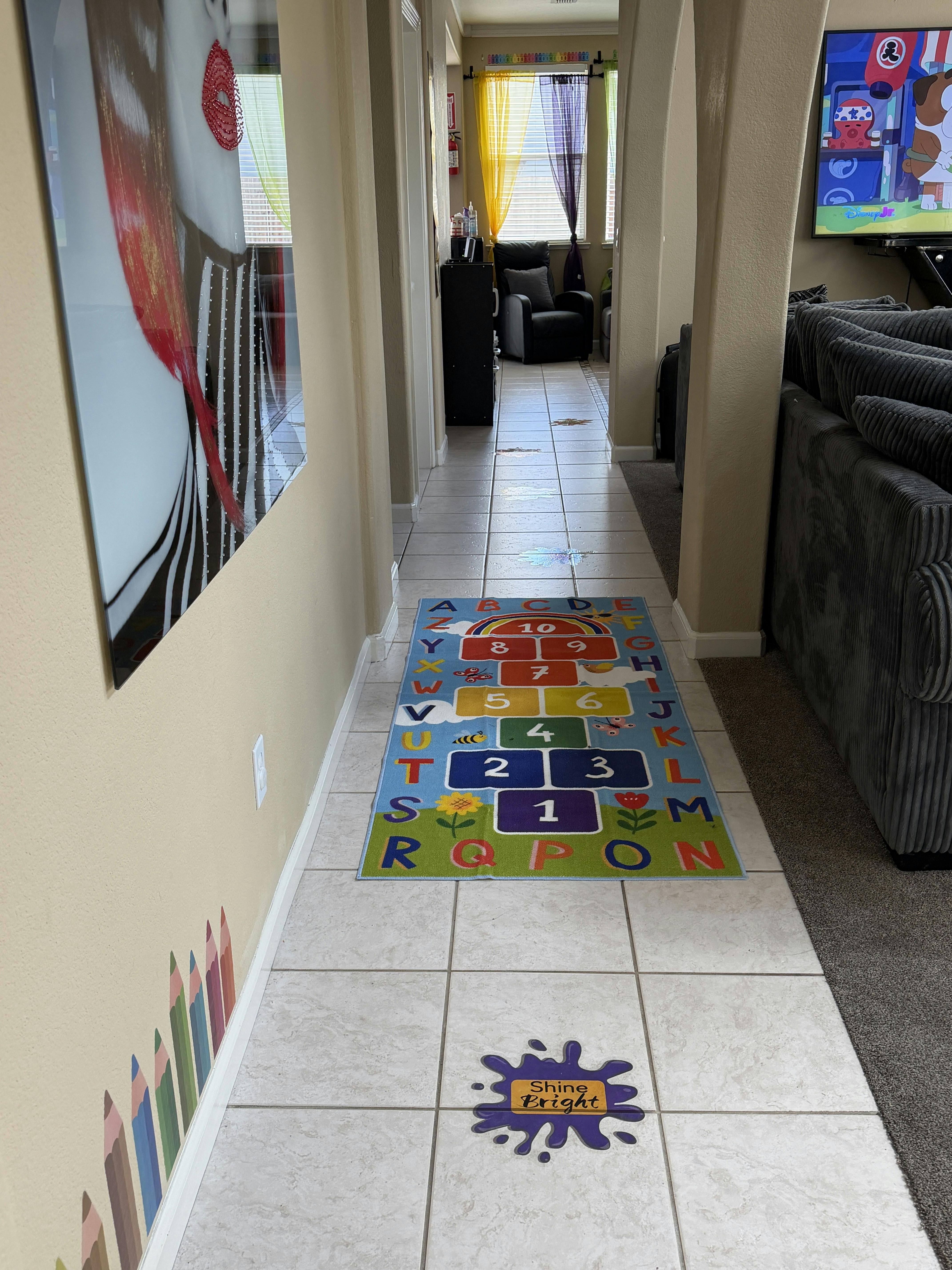 Colorful hopscotch rug on a tiled hallway floor, with text "Shine Bright" sticker
