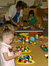 Adult and children playing with colorful building blocks at tables