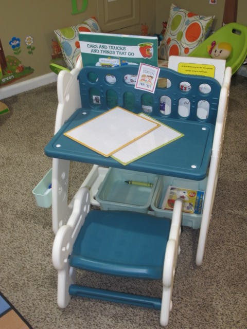 Child's blue and white activity desk with paper and a book