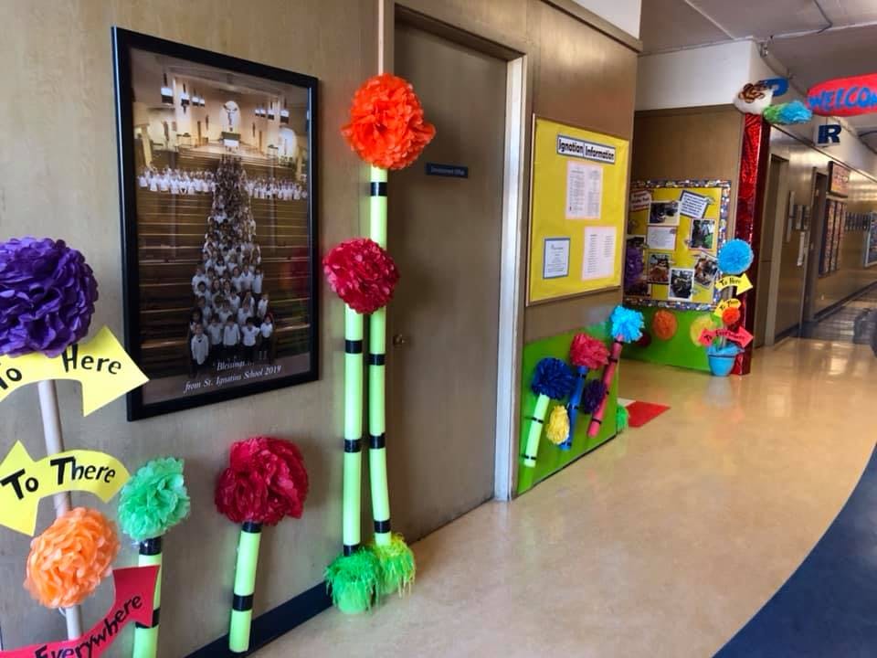Hallway decorated with colorful pom-poms and signs pointing "Here" and "To There"