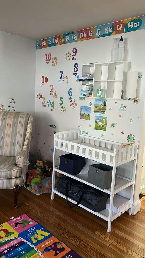 White changing table against a nursery wall with educational stickers