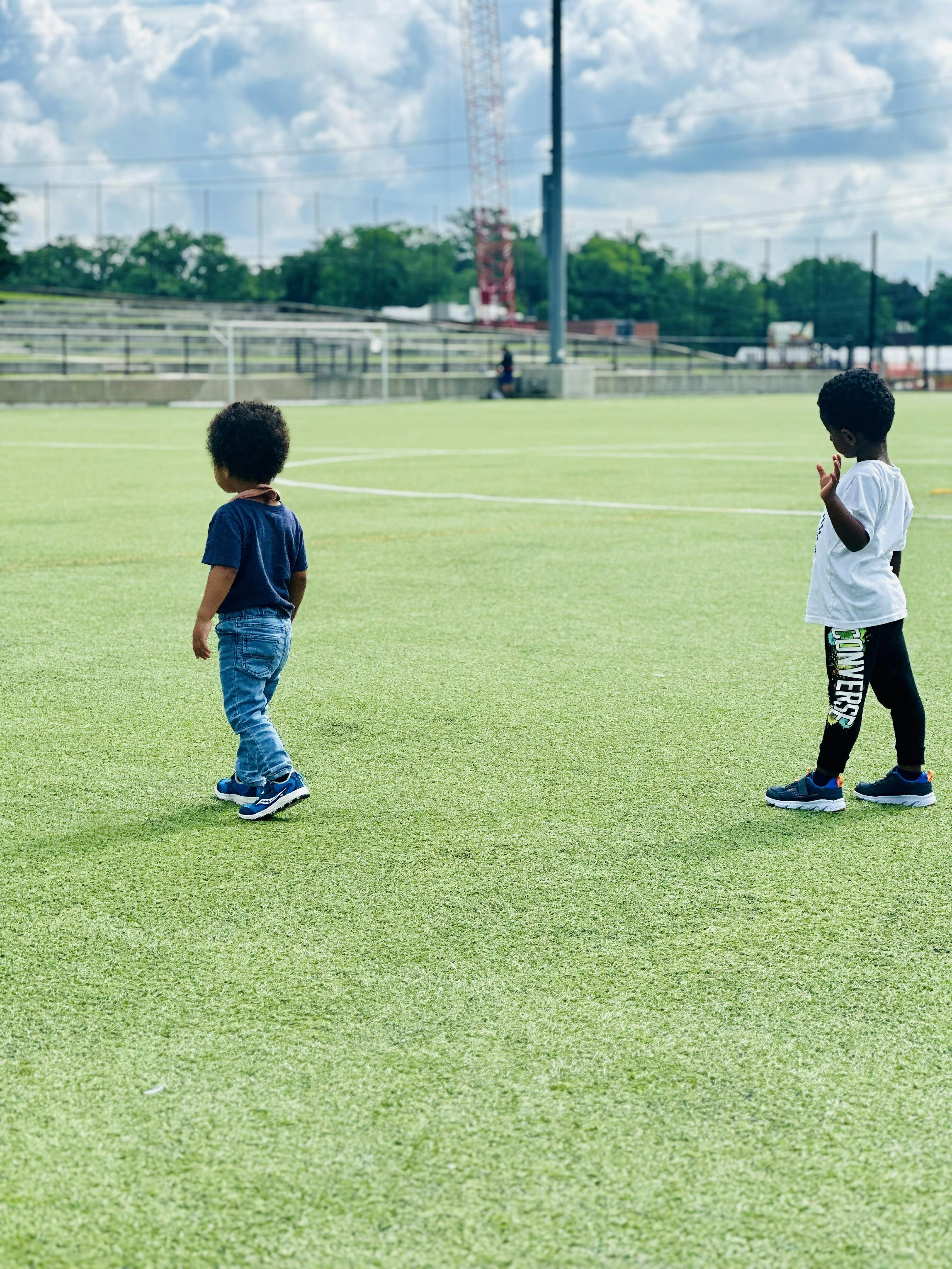 Two children standing on a green field