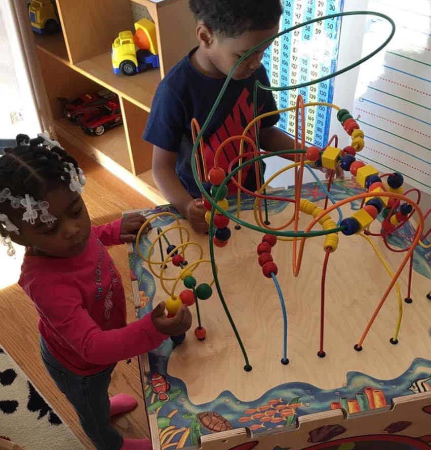 Two children playing with a bead maze toy