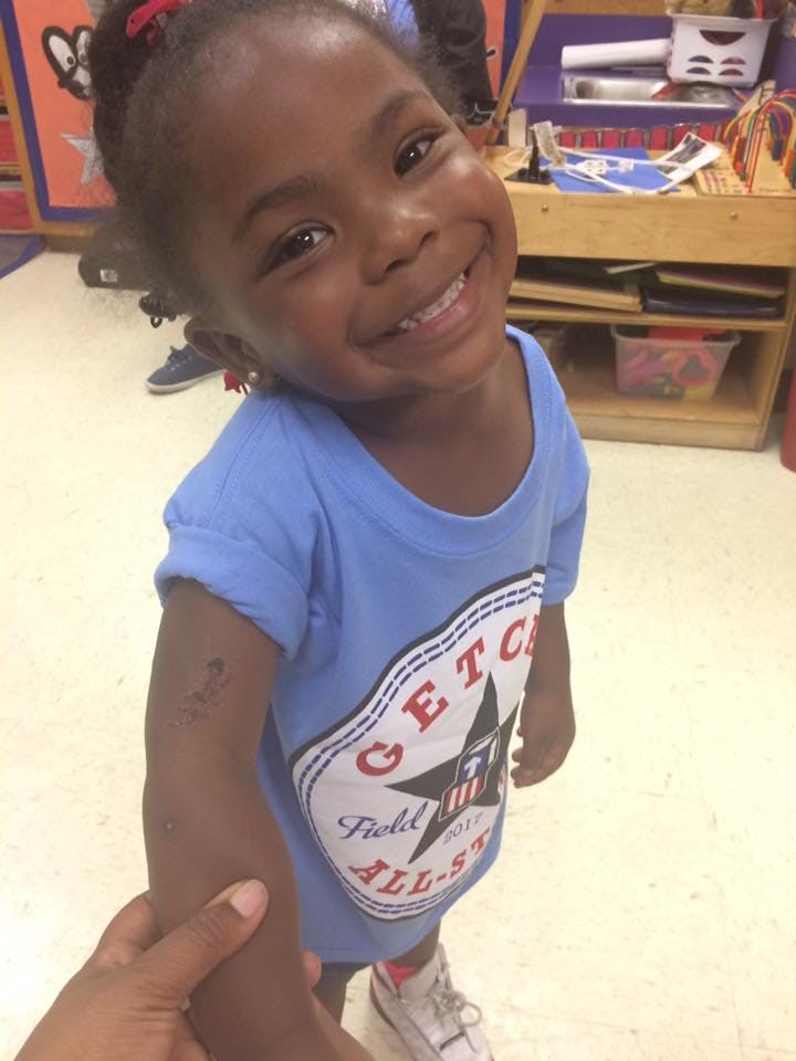 Child in a blue shirt smiling at the camera
