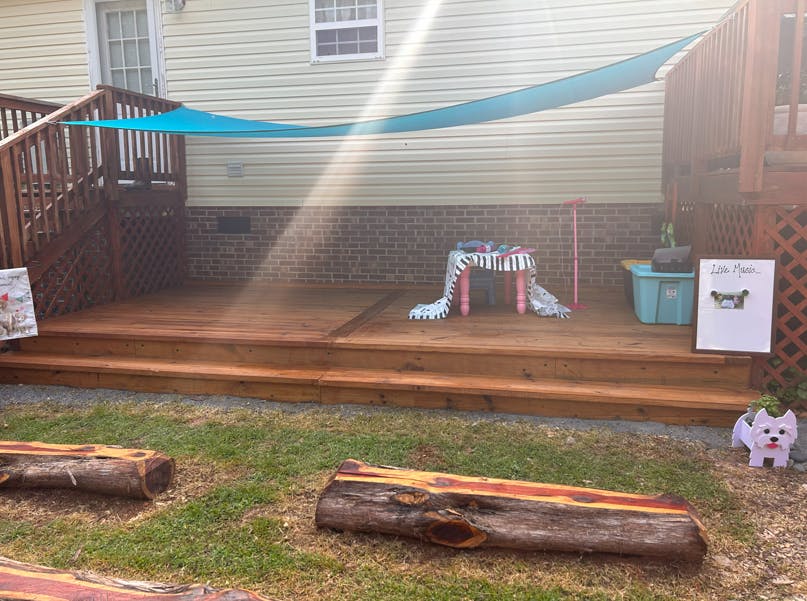 Outdoor wooden deck with a small table, a toy microphone, and a "Live Music" sign