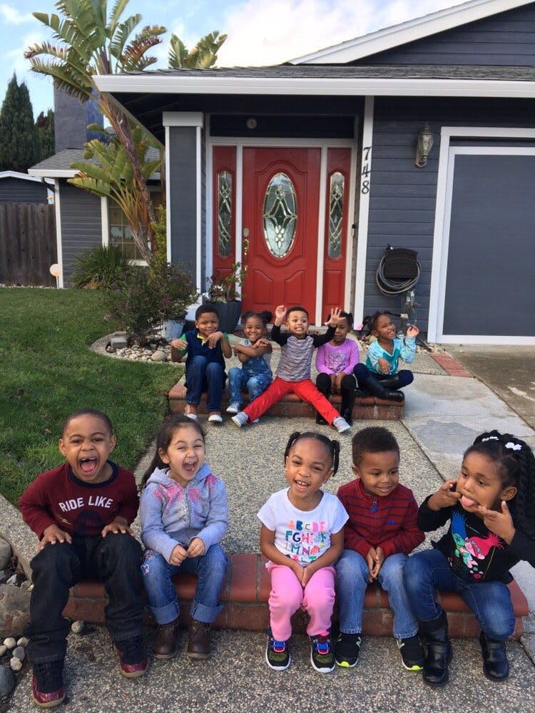 Group of children sitting on steps in front of a house