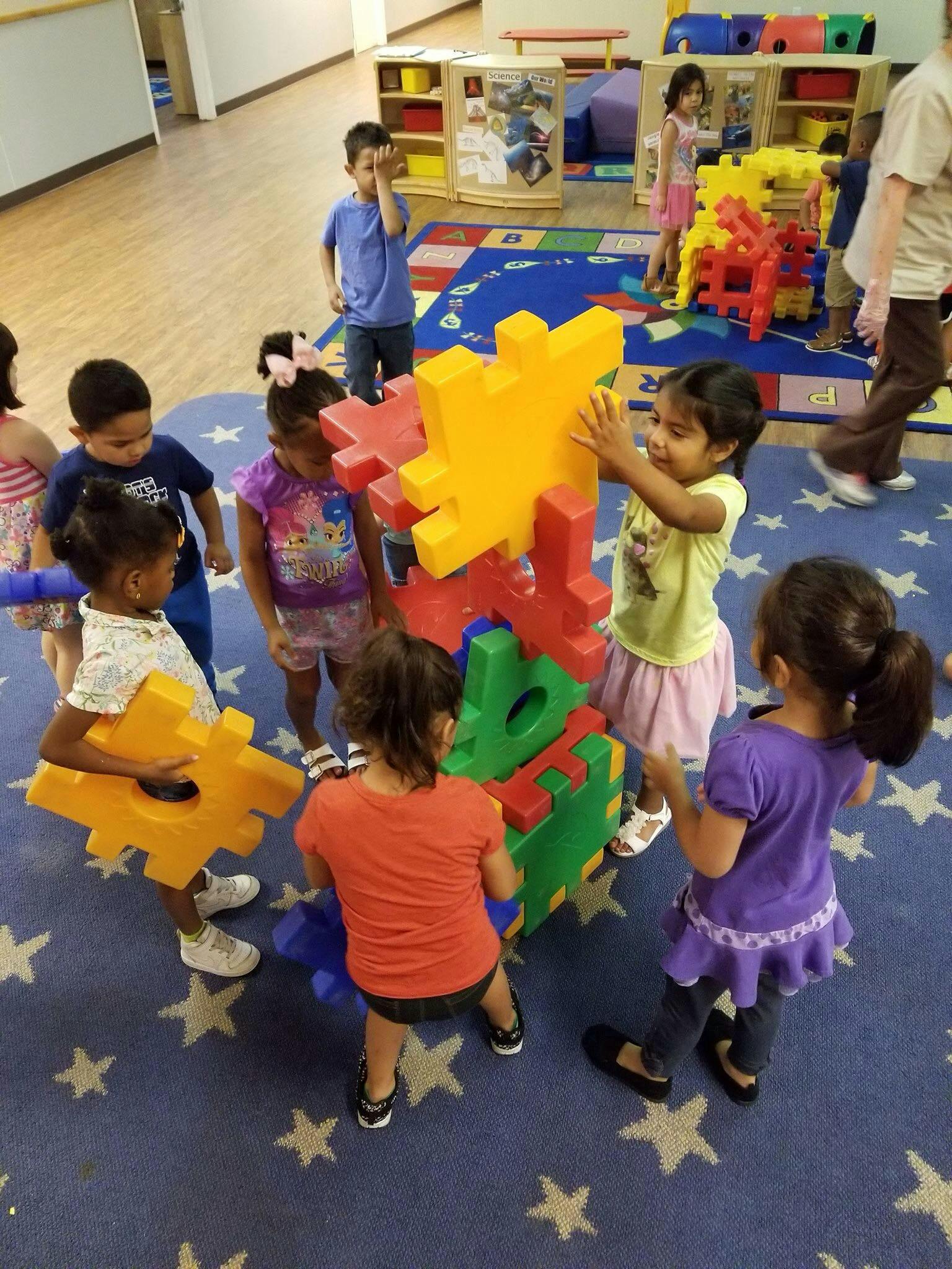 Children playing with large colorful interlocking blocks in a classroom