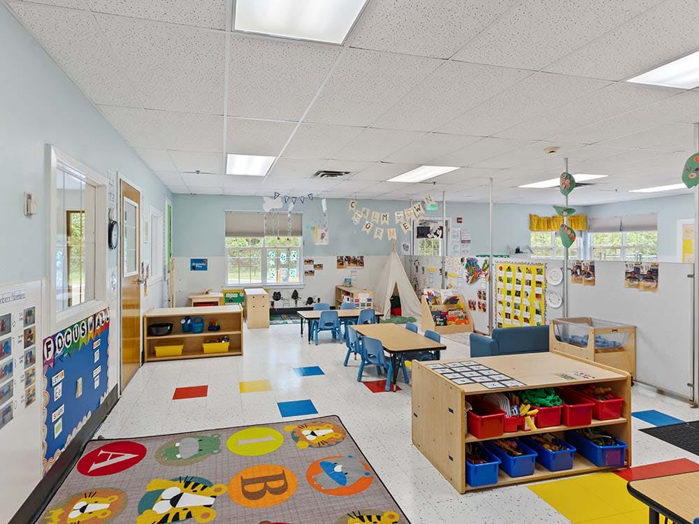 Colorful preschool classroom with tables, chairs, and learning materials