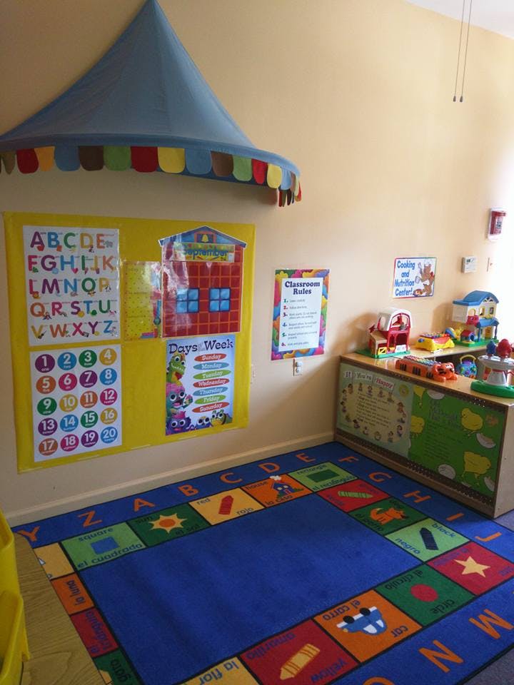 Classroom with alphabet and number charts, a colorful rug, and toys
