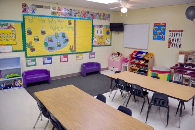 Classroom with tables, chairs, purple couches, and a bulletin board