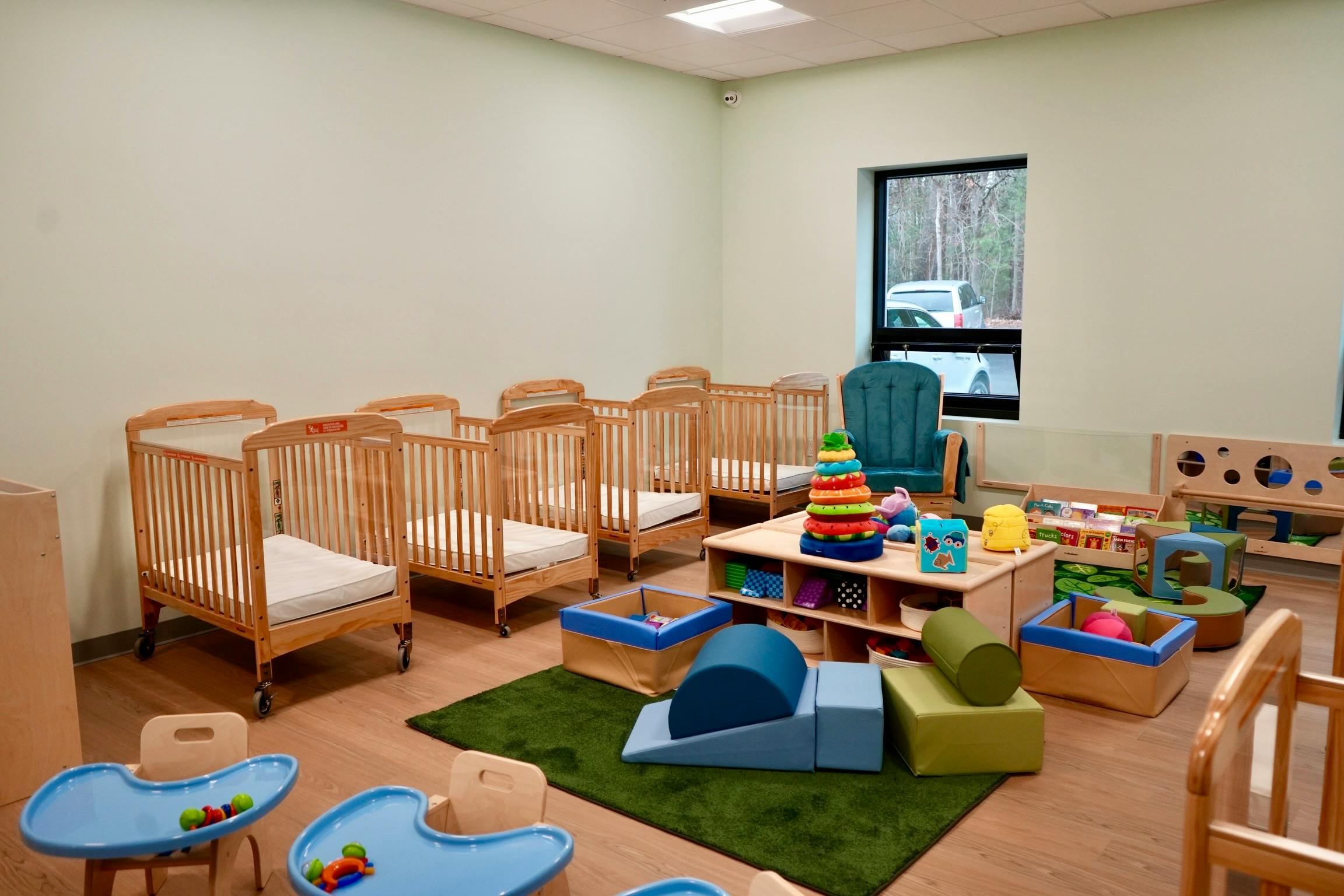 Nursery room with multiple cribs, play mats, and toys
