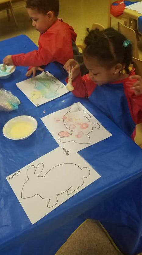 Two children painting bunny cutouts at a table
