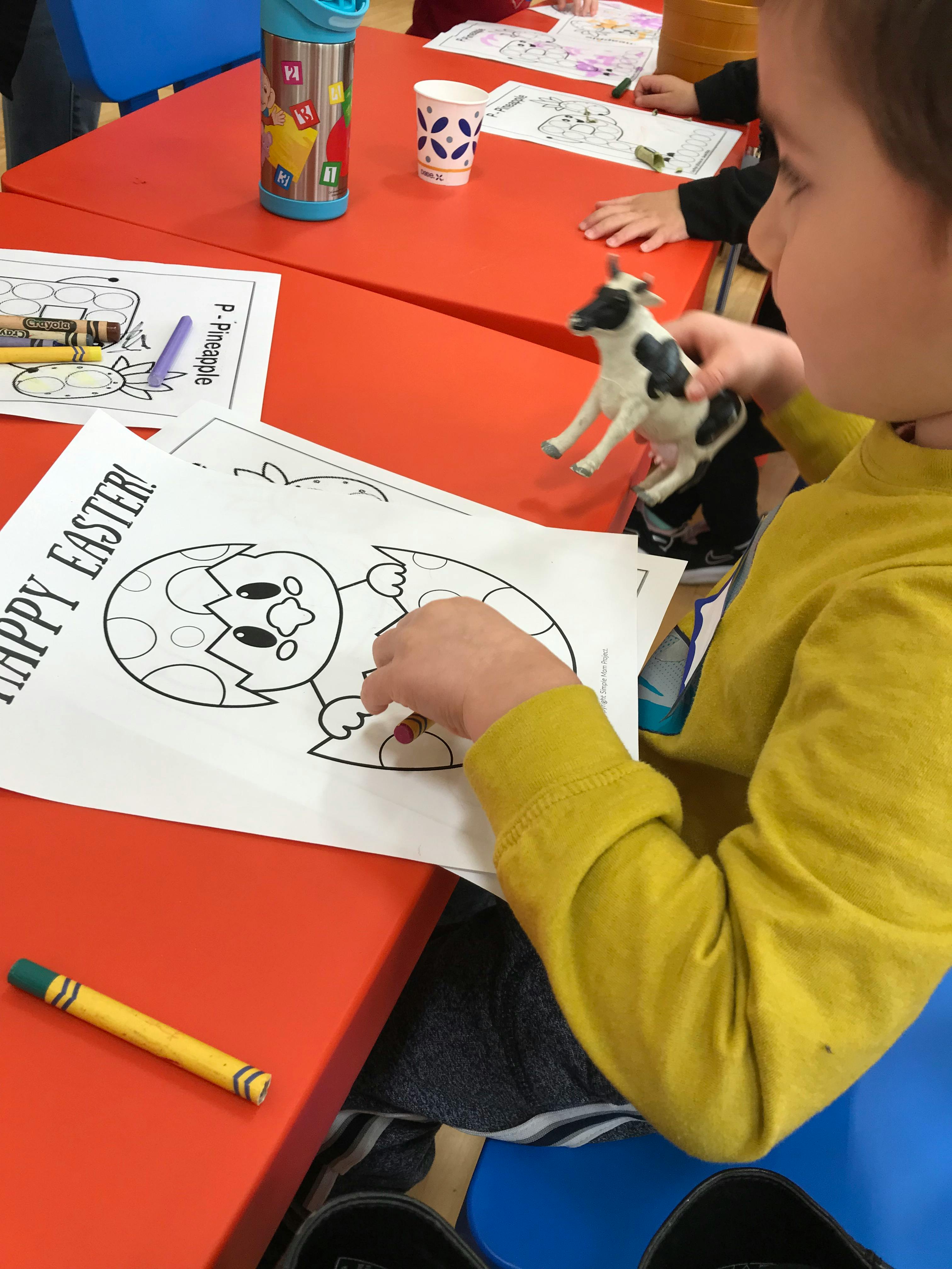 Child coloring an Easter chick picture at a table