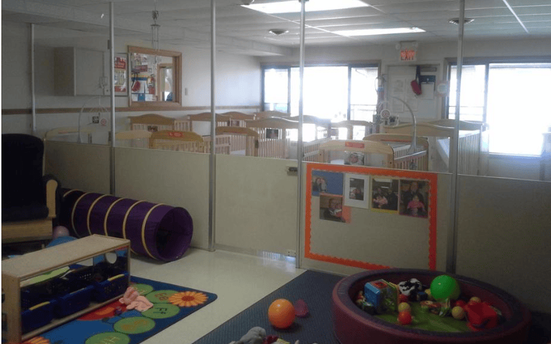 Cribs separated by partitions in a daycare or nursery room