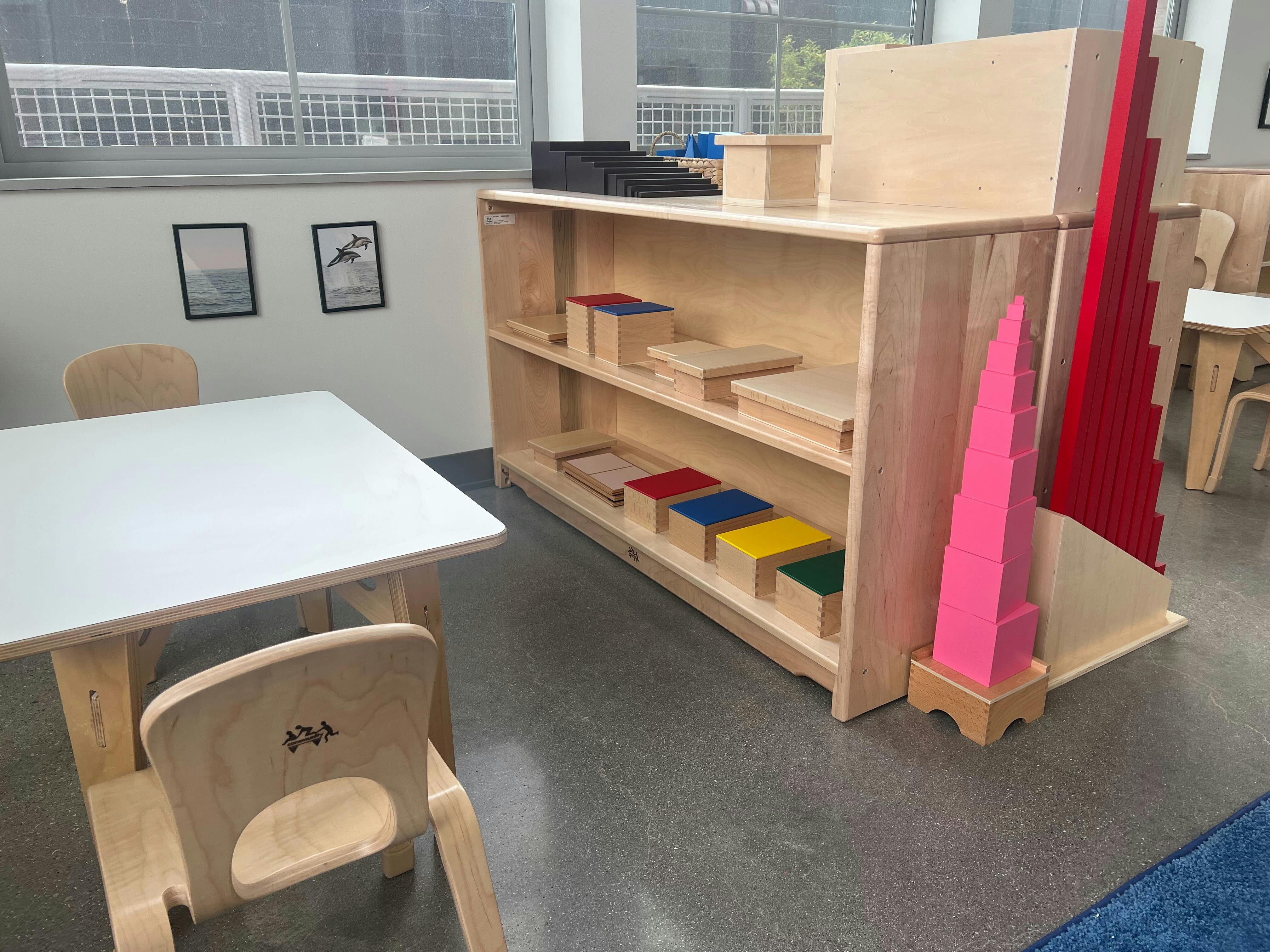 Classroom with wooden shelves holding colorful blocks and a small table with chairs