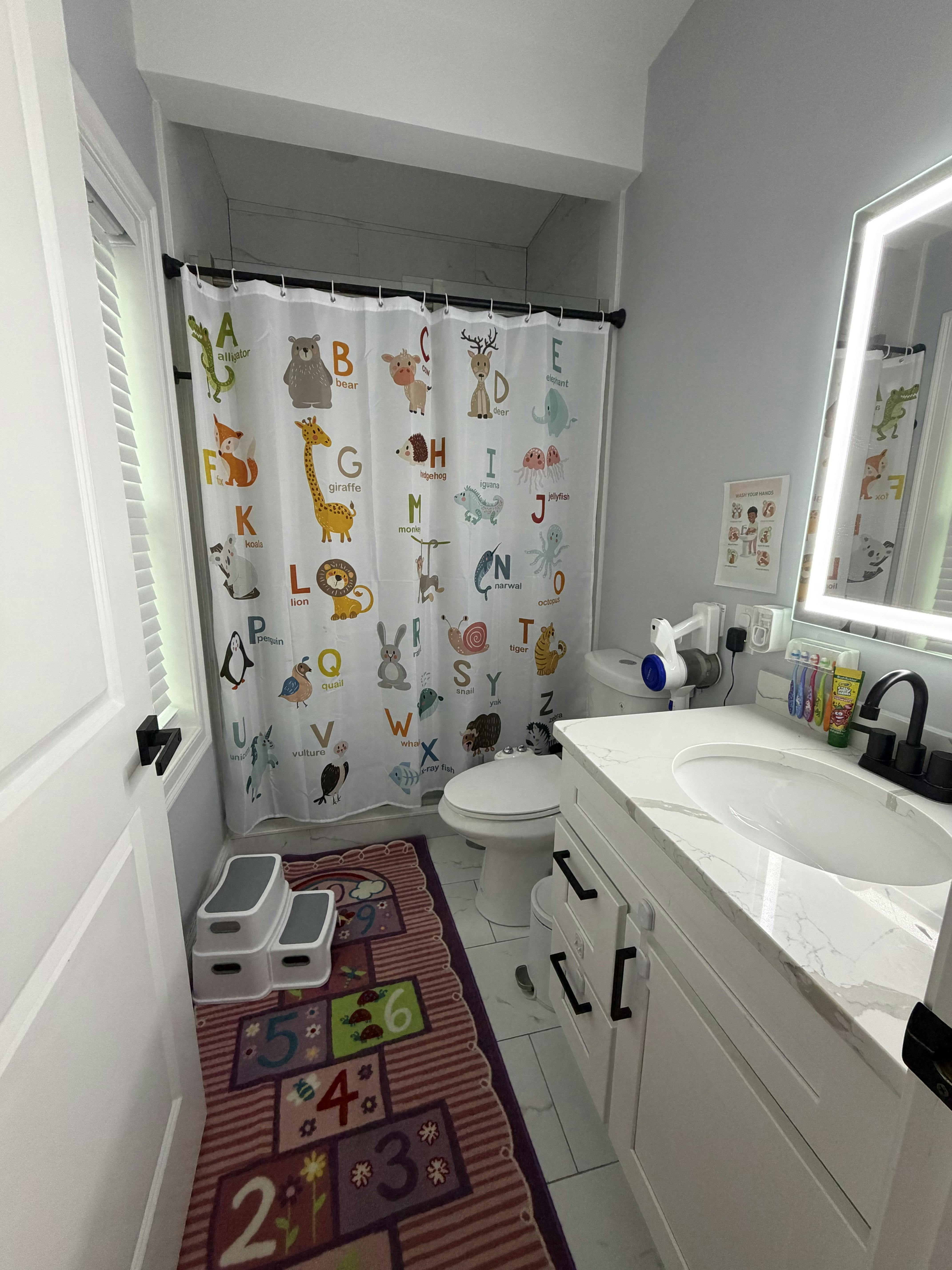 Bathroom featuring an alphabet animal shower curtain and a numbered rug