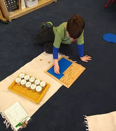 Child on floor working with a blue and tan puzzle-colored puzzle-like object