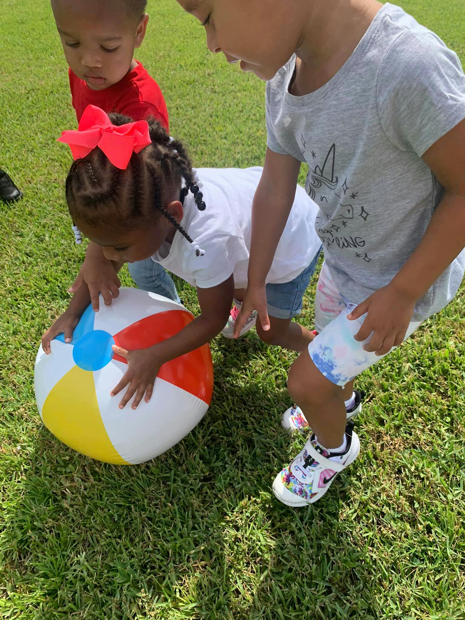 Three children playing with a beach ball on grass
