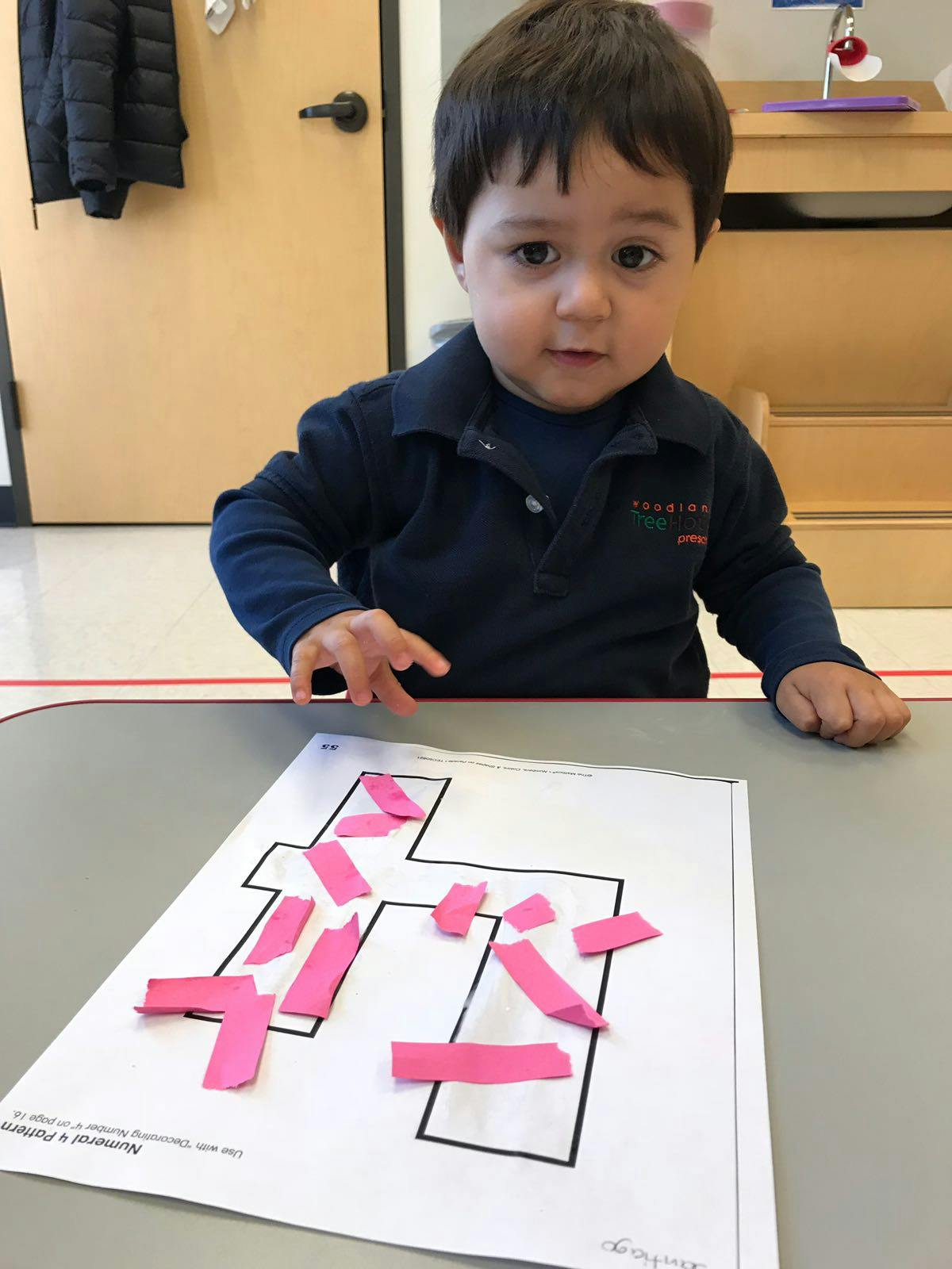 Child at a table with paper and pink strips