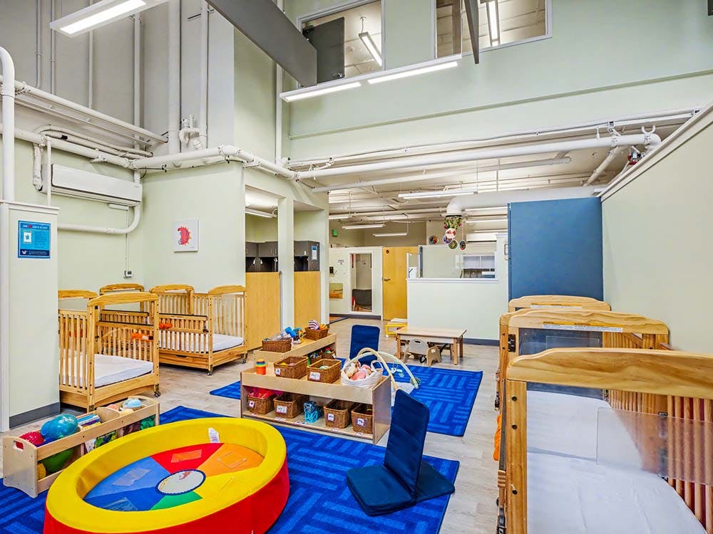 Cribs, playmats, and toys in a childcare room