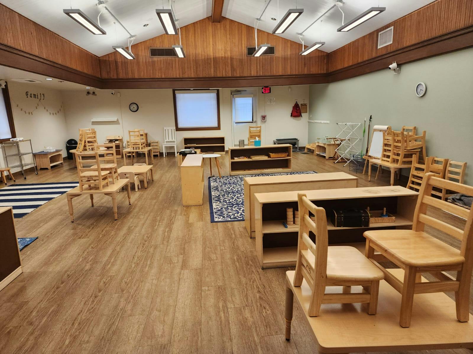 Classroom with small wooden tables and chairs, some stacked