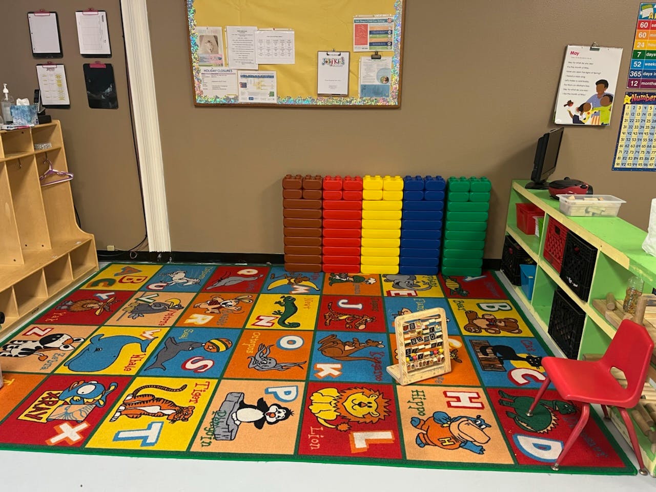 Classroom with alphabet rug, colorful blocks, and small red chair