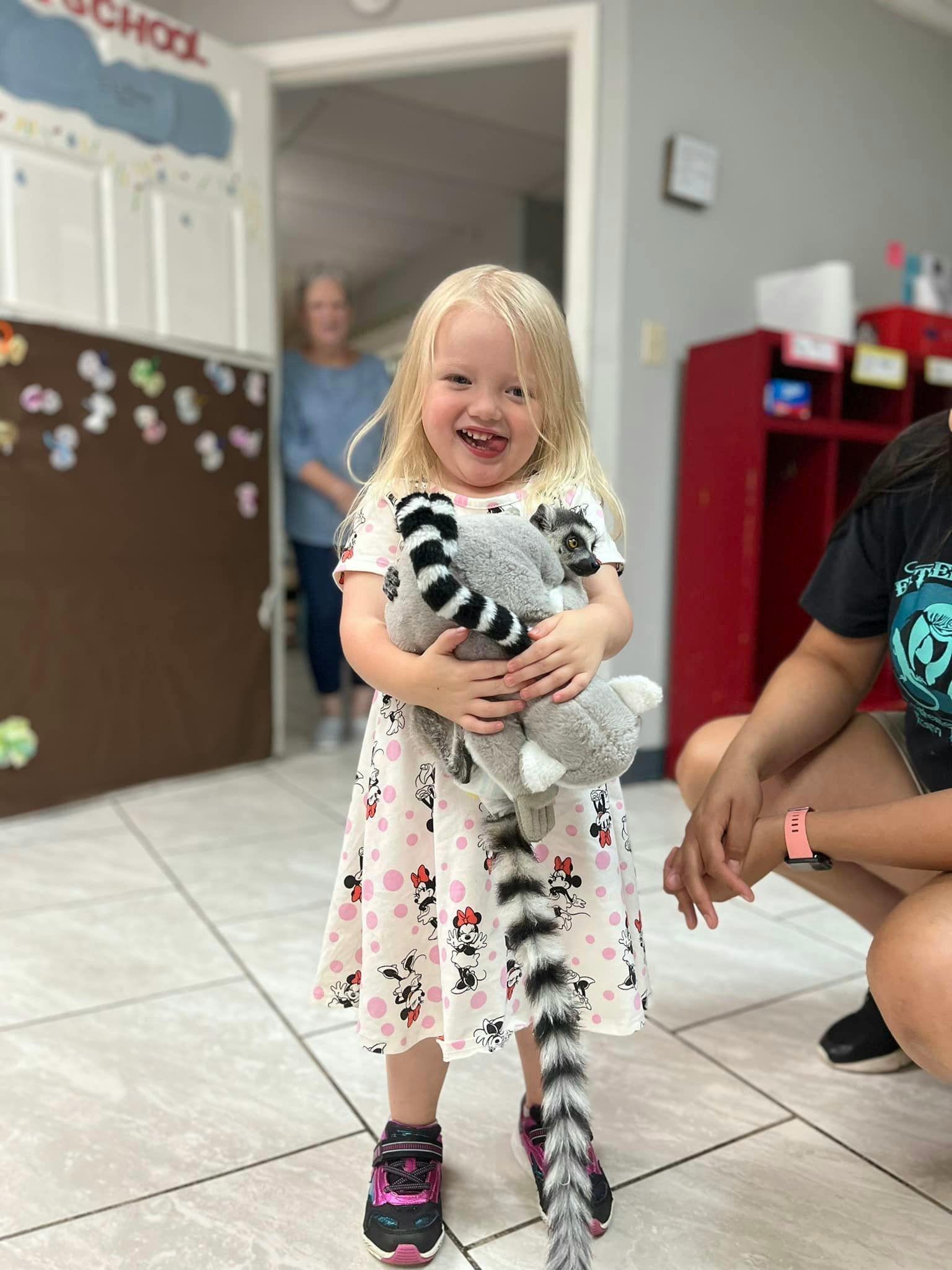 Child holding a stuffed animal with a long striped tail