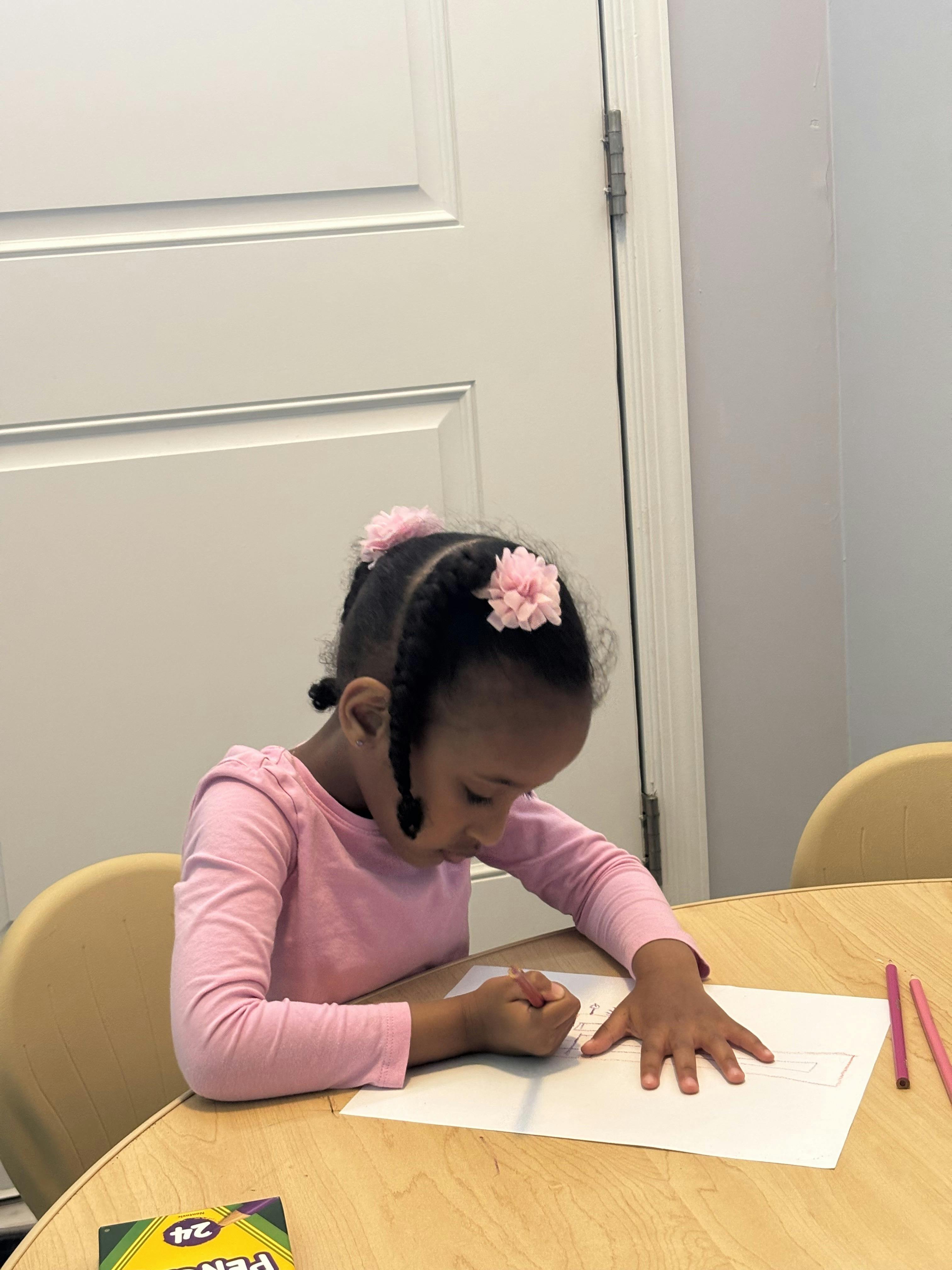 Child drawing on paper at a table