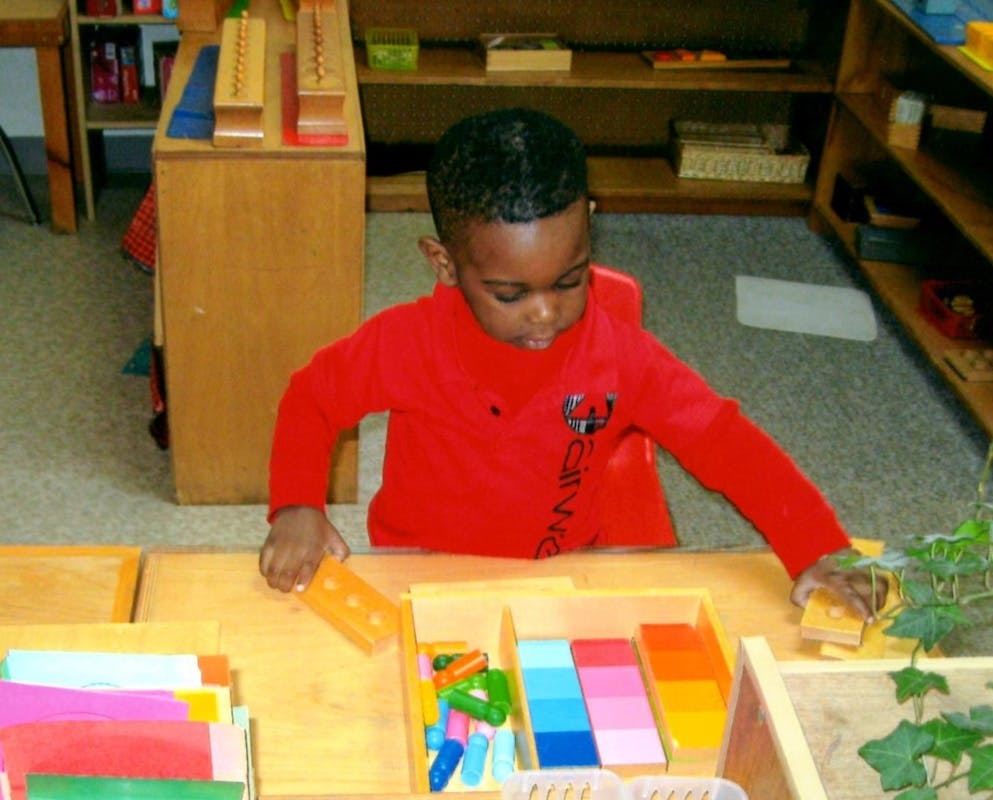 Child in red shirt playing with colorful blocks at a table