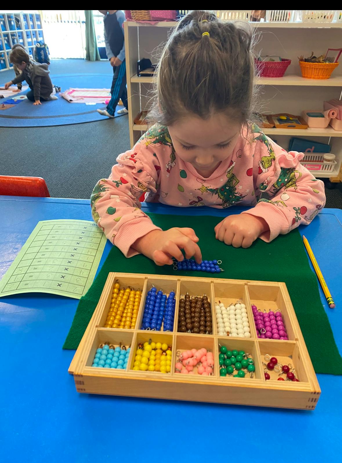 Child working with colorful beads at a table in a classroom