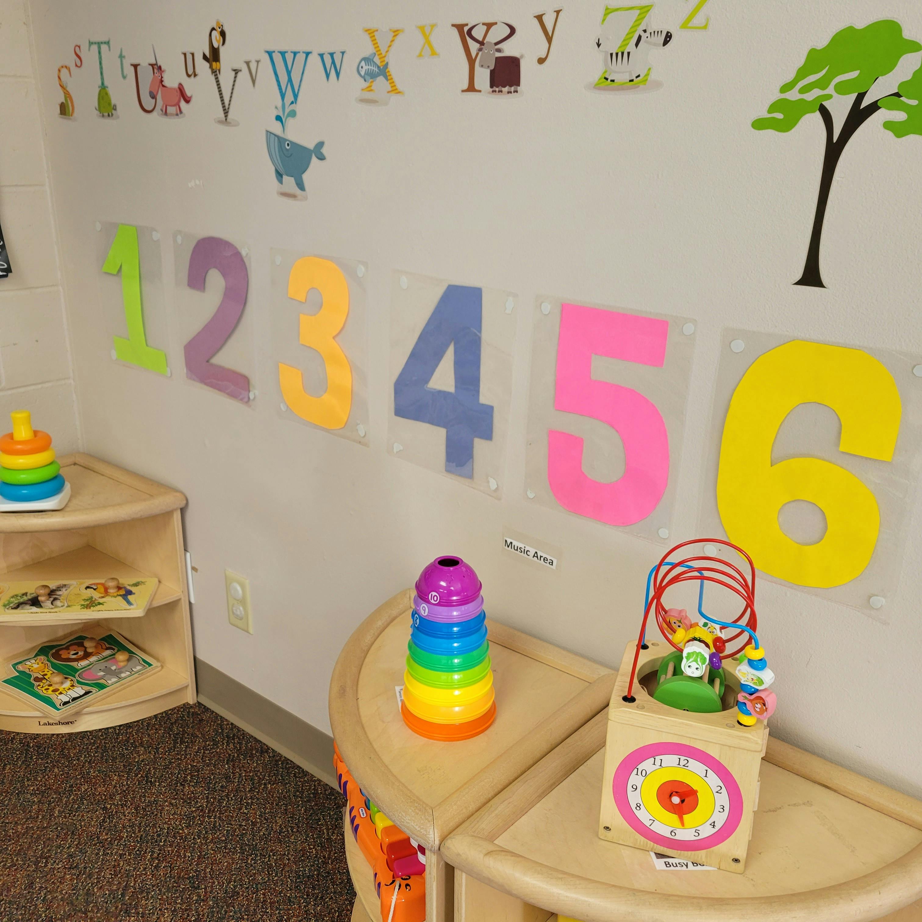 Classroom wall with colorful numbers and alphabet letters, toys on shelves