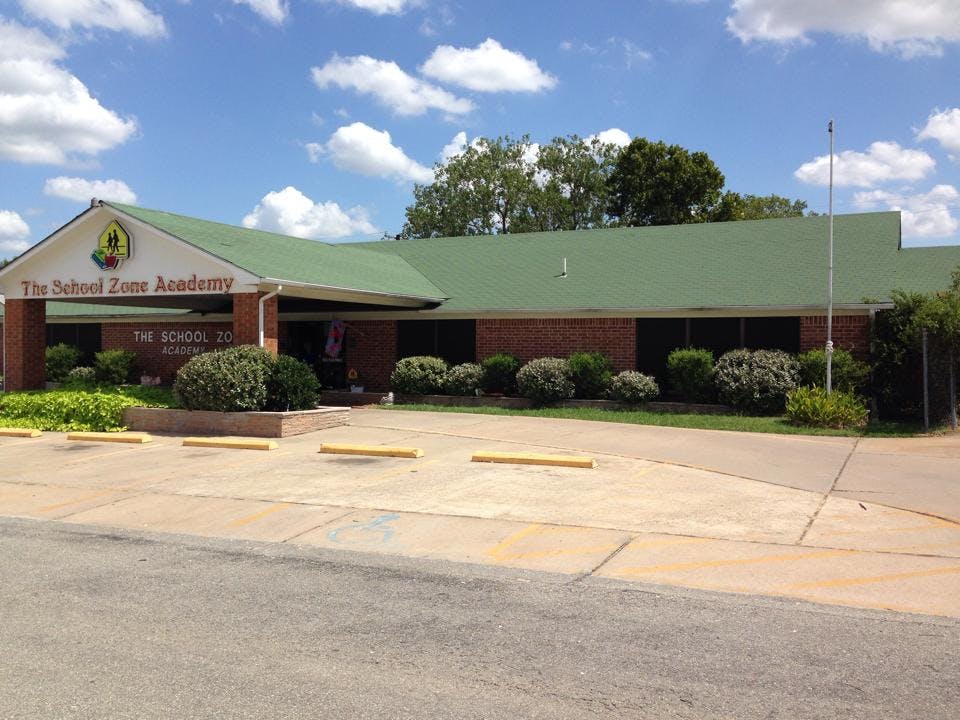 The School Zone Academy building with a green roof and brick facade