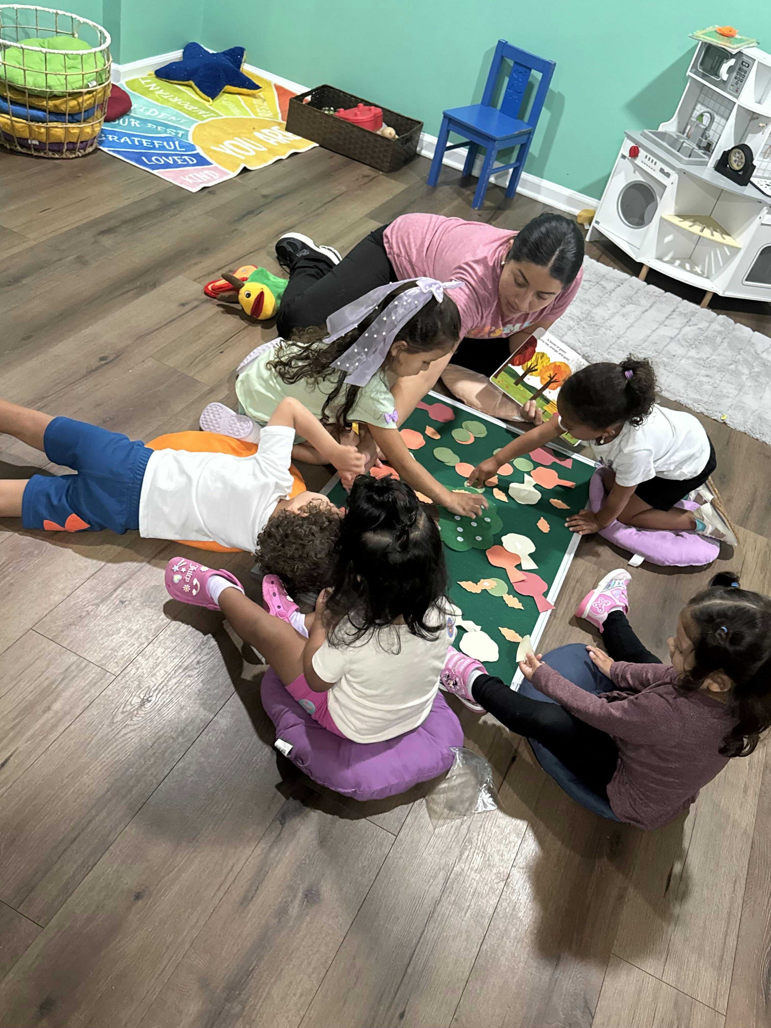 Group of children and an adult sitting on the floor using a felt activity board