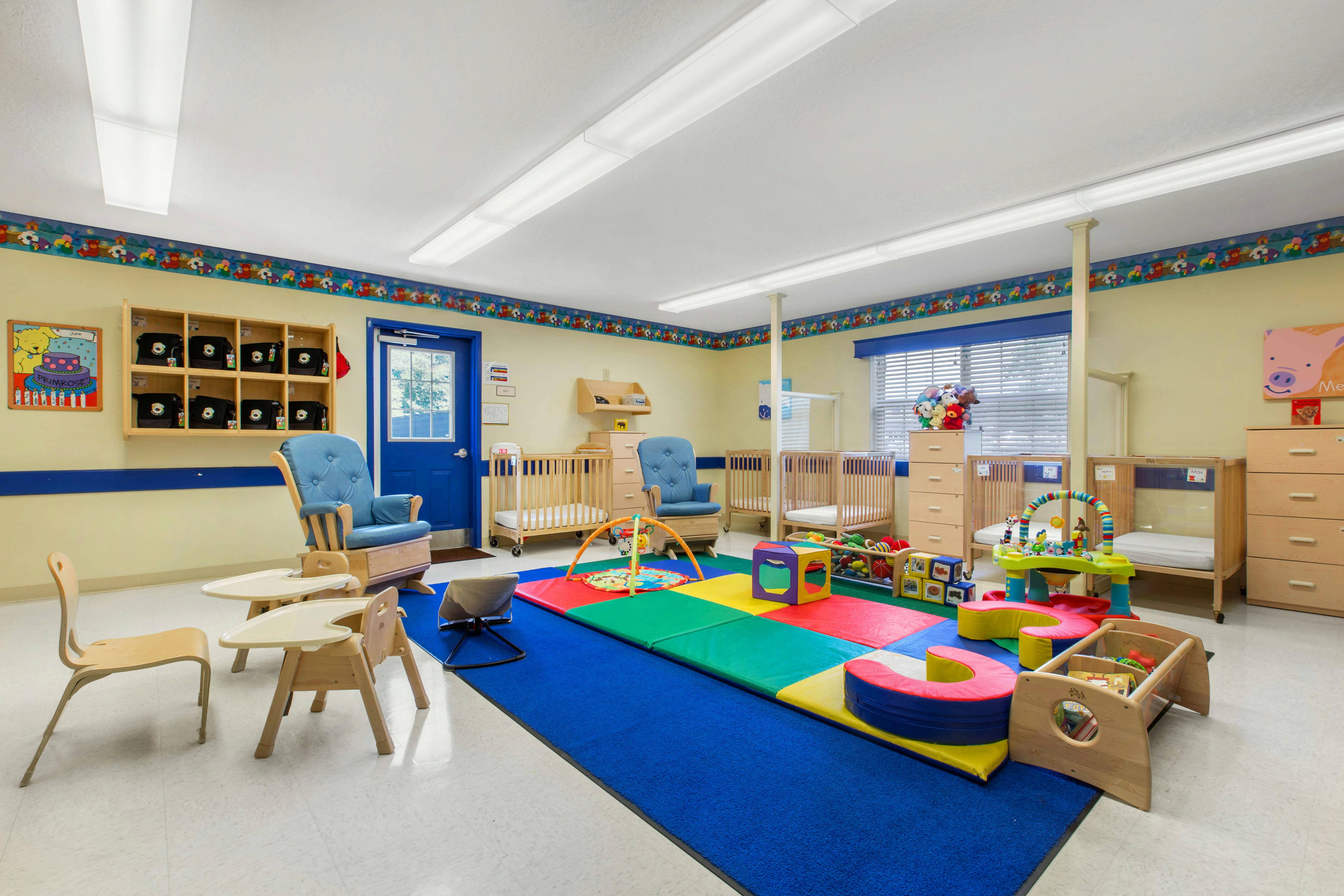 Colorful playroom with cribs, chairs, and play mats