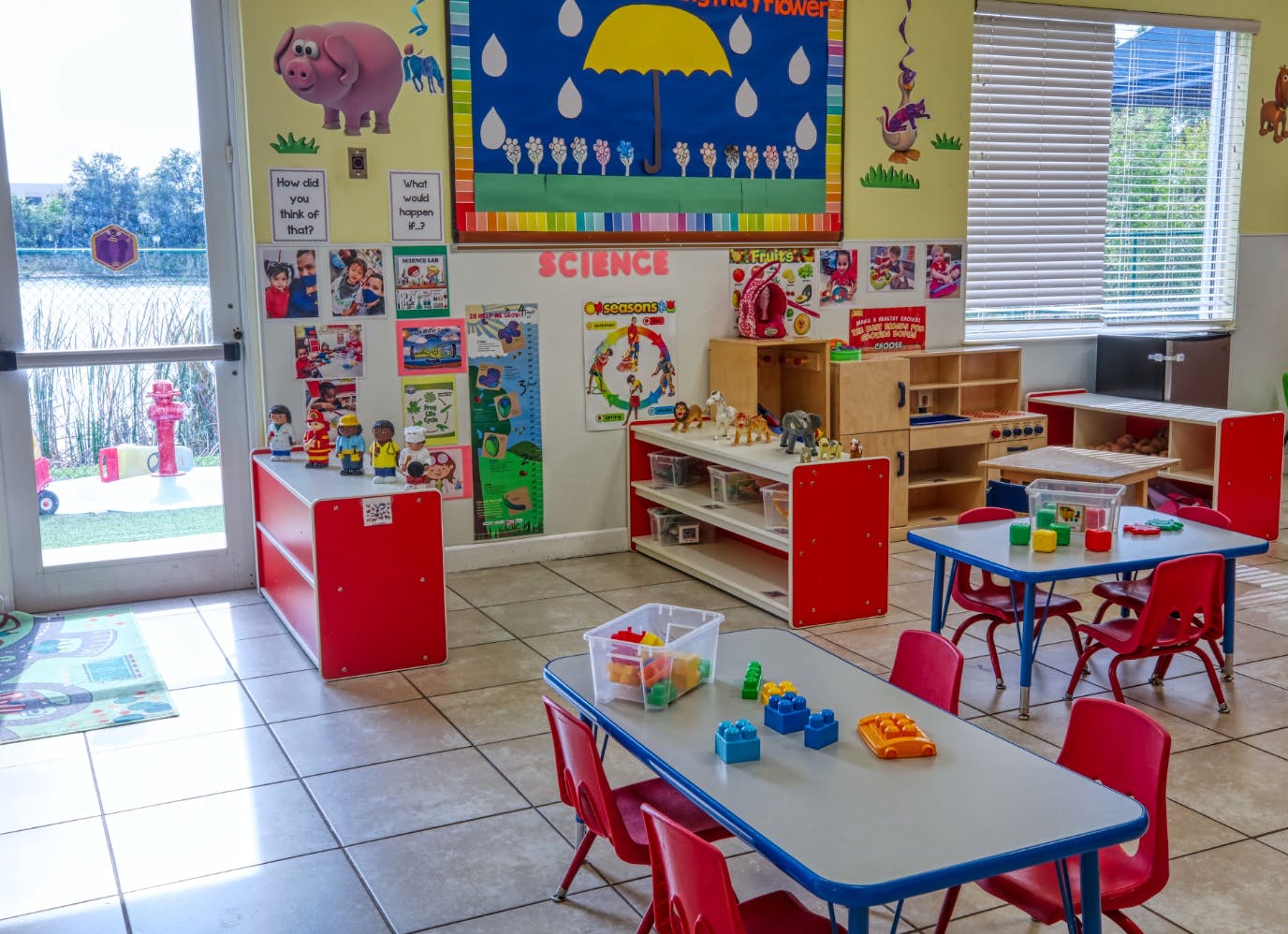 Classroom with child-sized tables and chairs, shelves, and educational posters