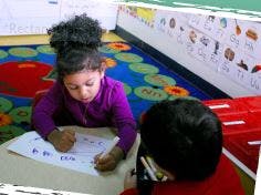 Child drawing at a table with another child