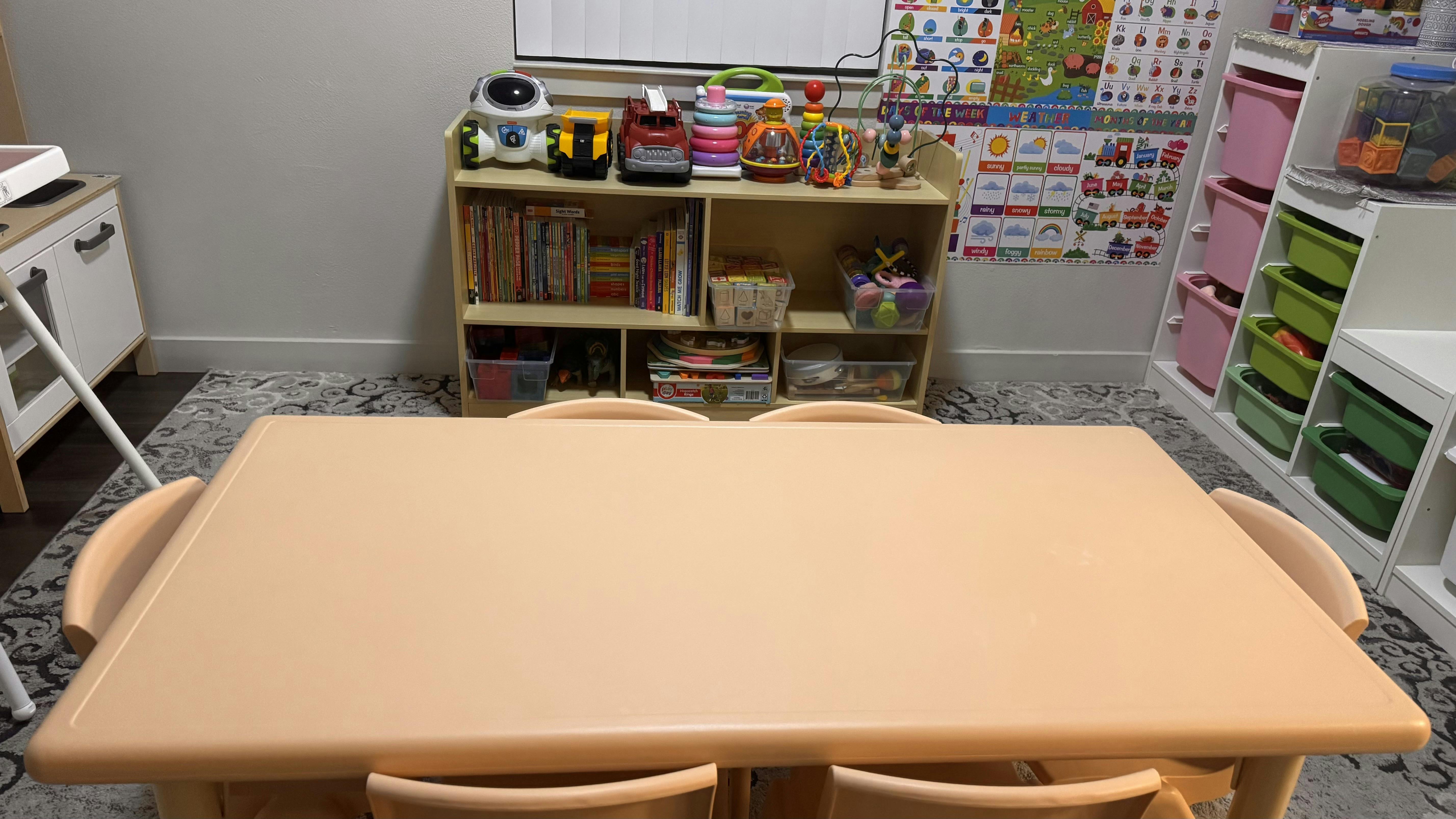 Playroom with a table and chairs in the foreground, toy shelves in the background