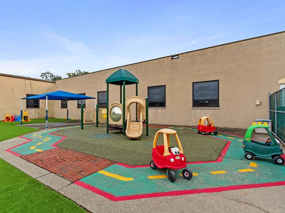 Outdoor playground with artificial turf, play structure, and toy cars