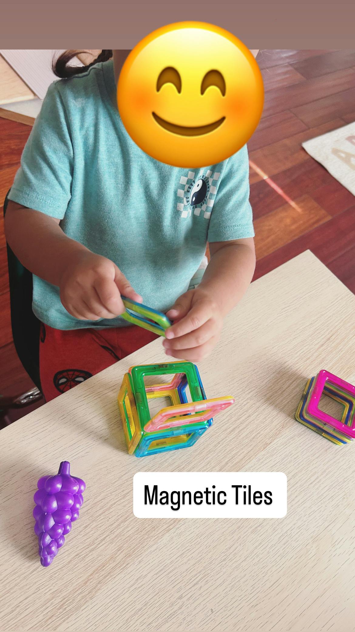 Child playing with colorful magnetic tiles on a table