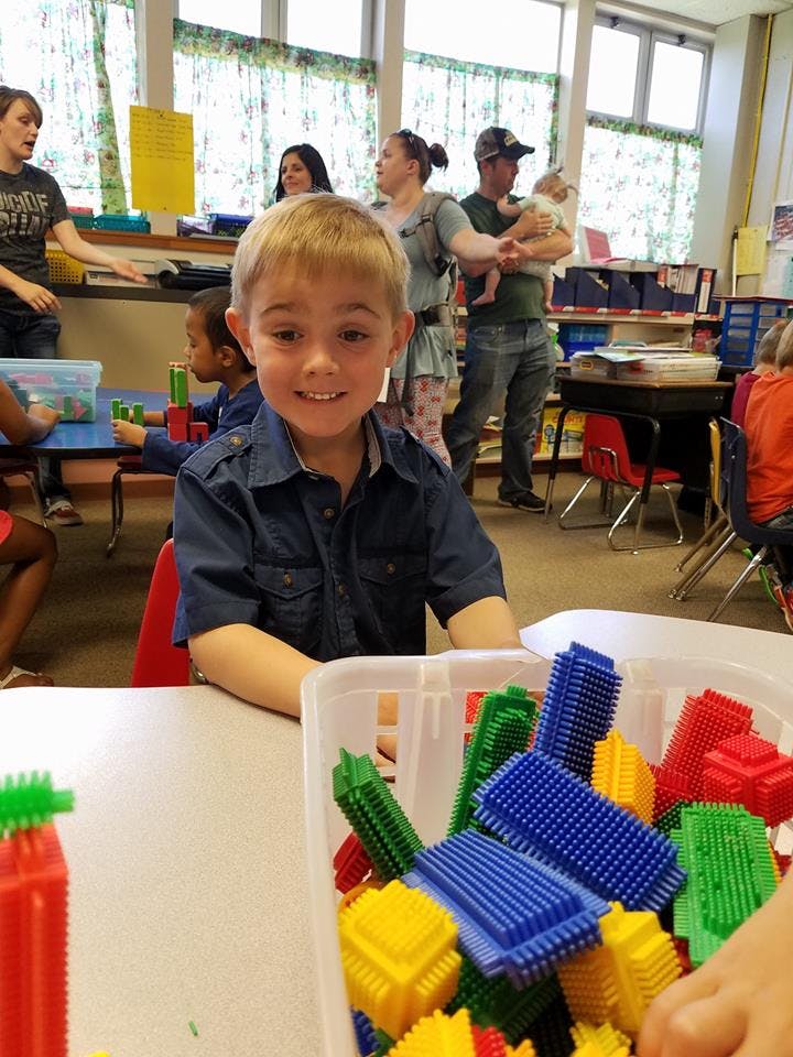 Child sitting at a table with building blocks in a classroom