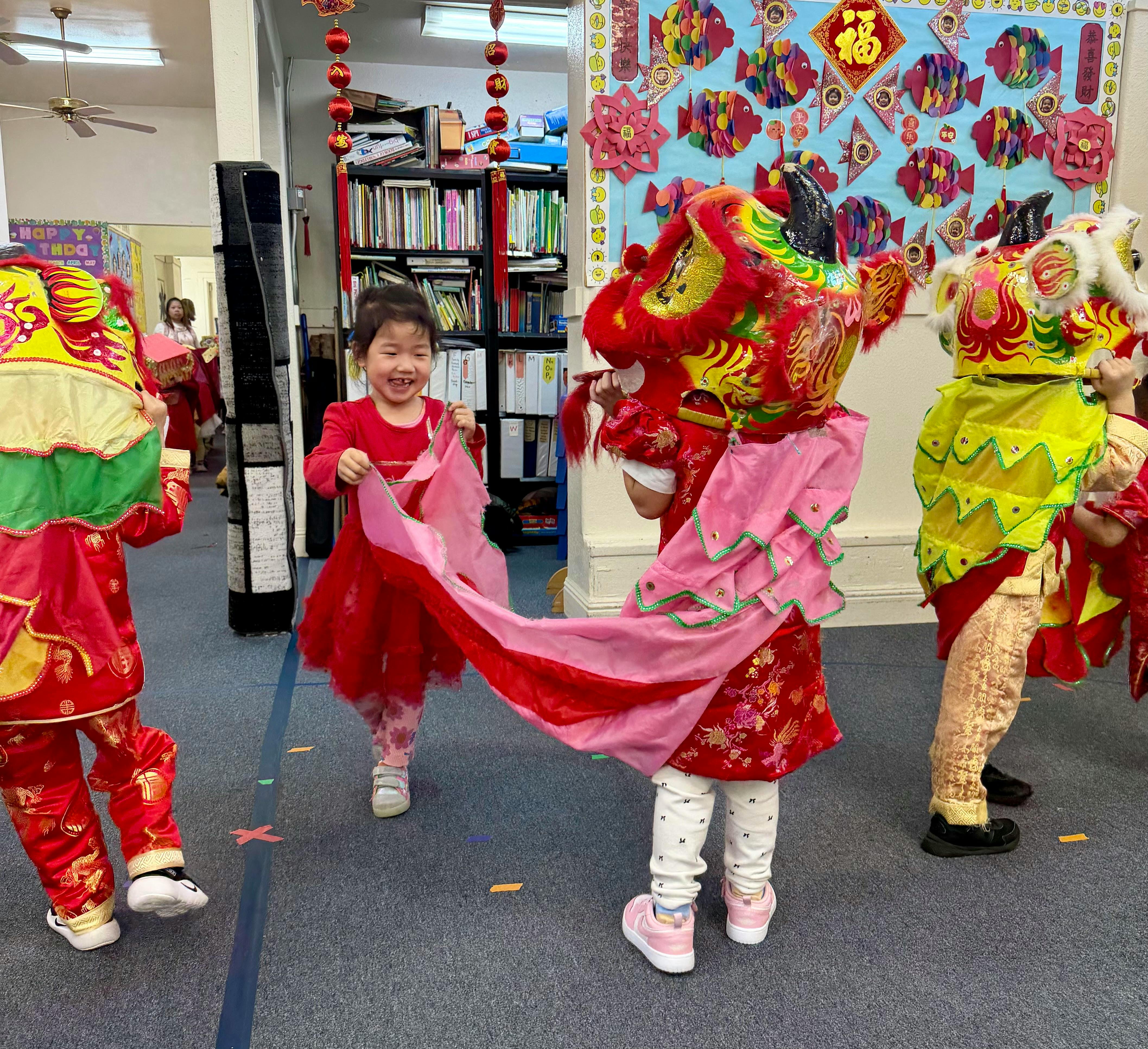 Children wearing lion dance costumes in a classroom