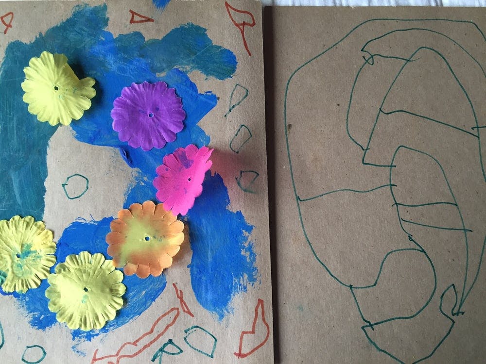 Child's artwork with colorful paper flowers on painted blue background