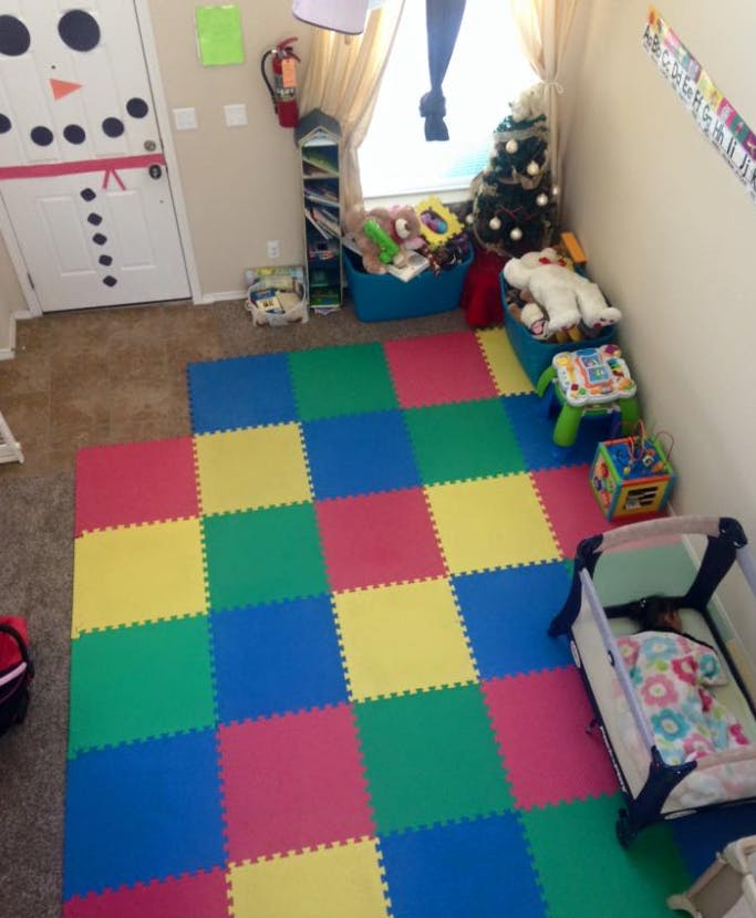 Playroom with colorful interlocking floor mats, crib, and snowman door decoration