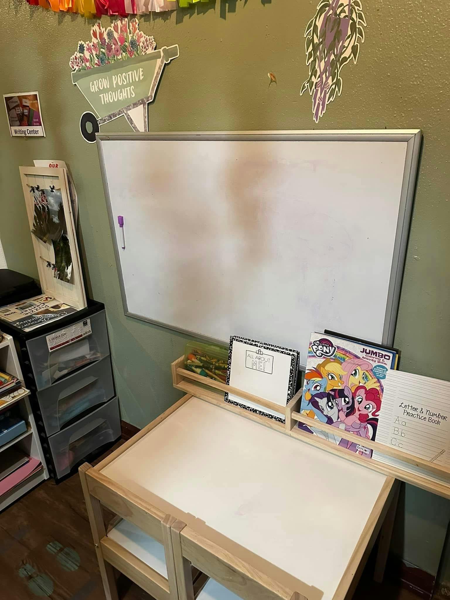 Whiteboard above a wooden child's desk with books