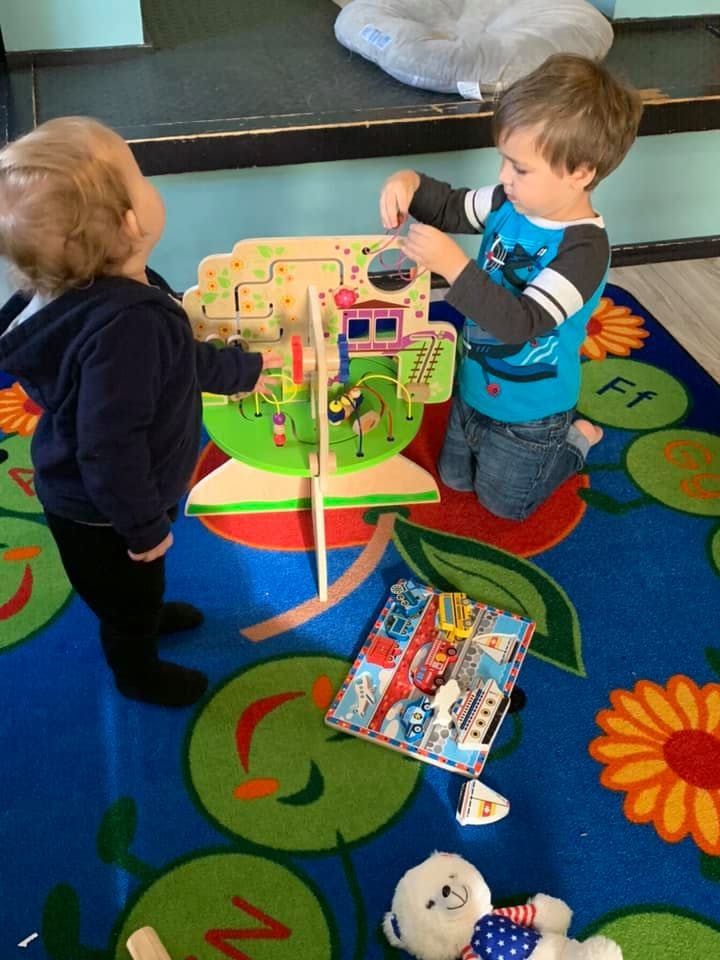 Two children playing with a wooden activity center