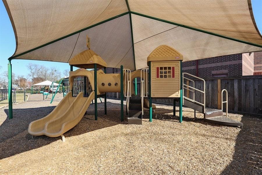 Playground with slides and climbing structures under a shade canopy