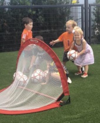 Children playing soccer with a small goal and portable goal